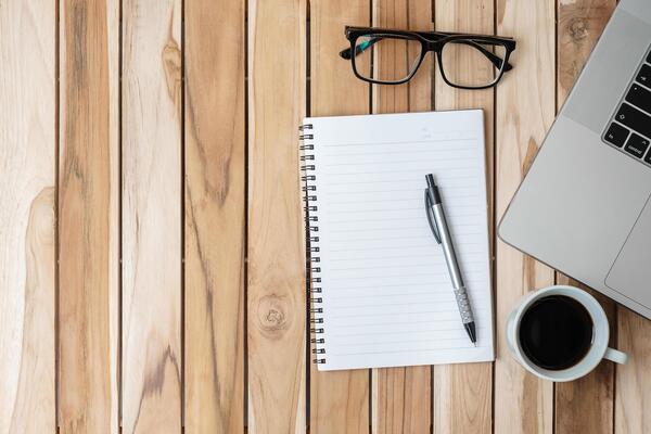 Notebook, glasses, and a cup of tea arranged in a calm setting